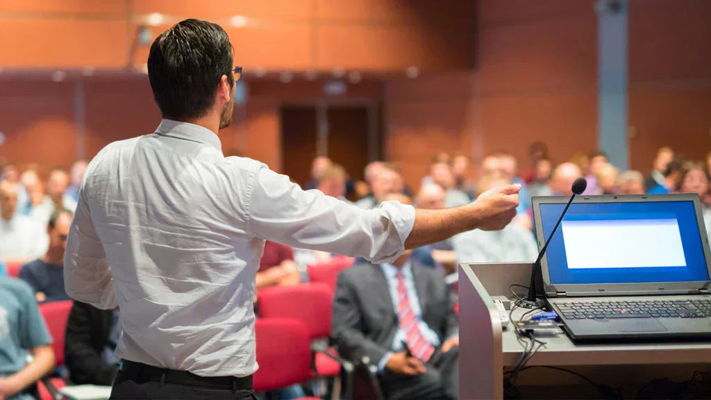 Professional presenter using a wireless presentation remote to engage an audience in a conference room.