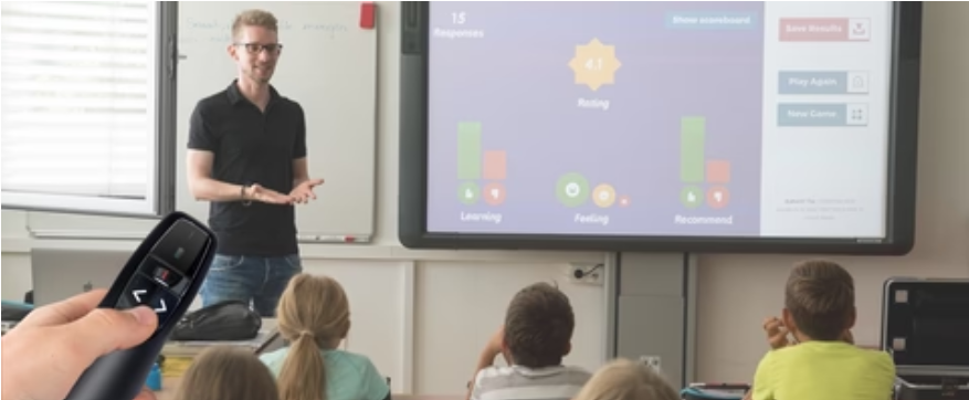 Teacher using a smart board with interactive feedback, engaging students. A hand in the foreground holds a presentation clicker, showing its classroom use.